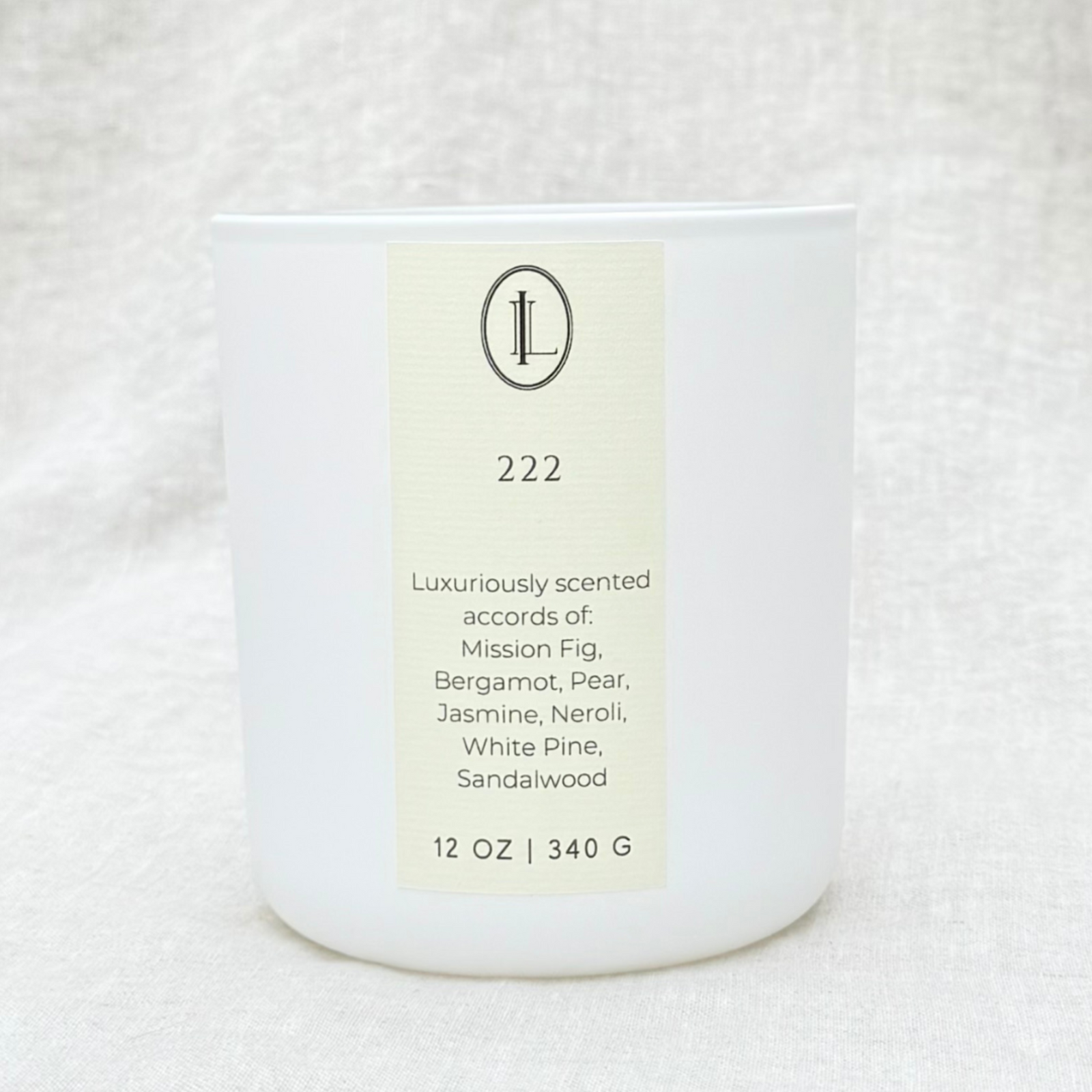 A white matte glass candle jar with a wood wick, labeled with '222' and a list of botanical scent notes including Mission Fig, Bergamot, Pear, Jasmine, Neroli, White Pine, Sandalwood.