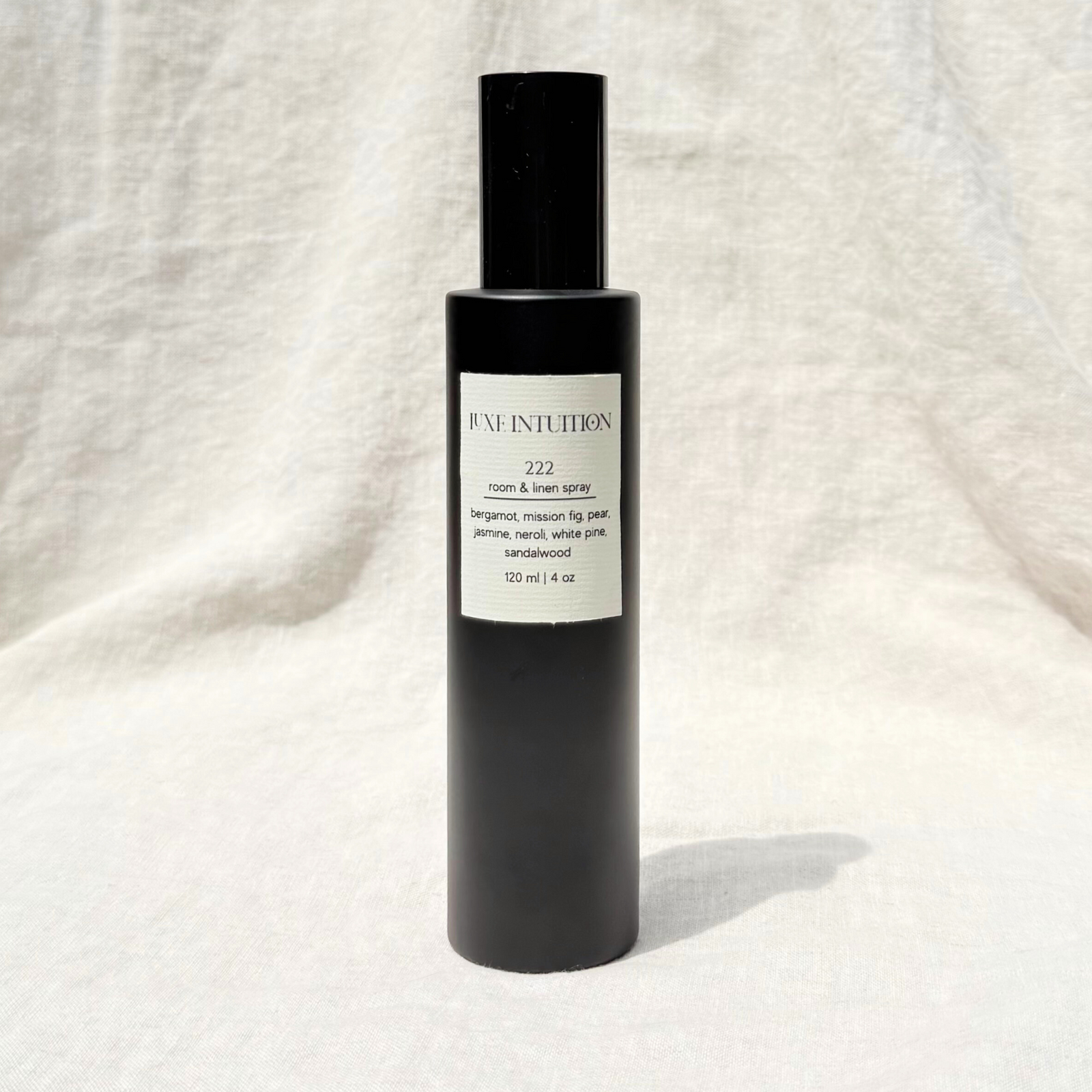 Bergamot and Fig scented room and linen spray with angel number label 222 on a black spray bottle resting on a linen background