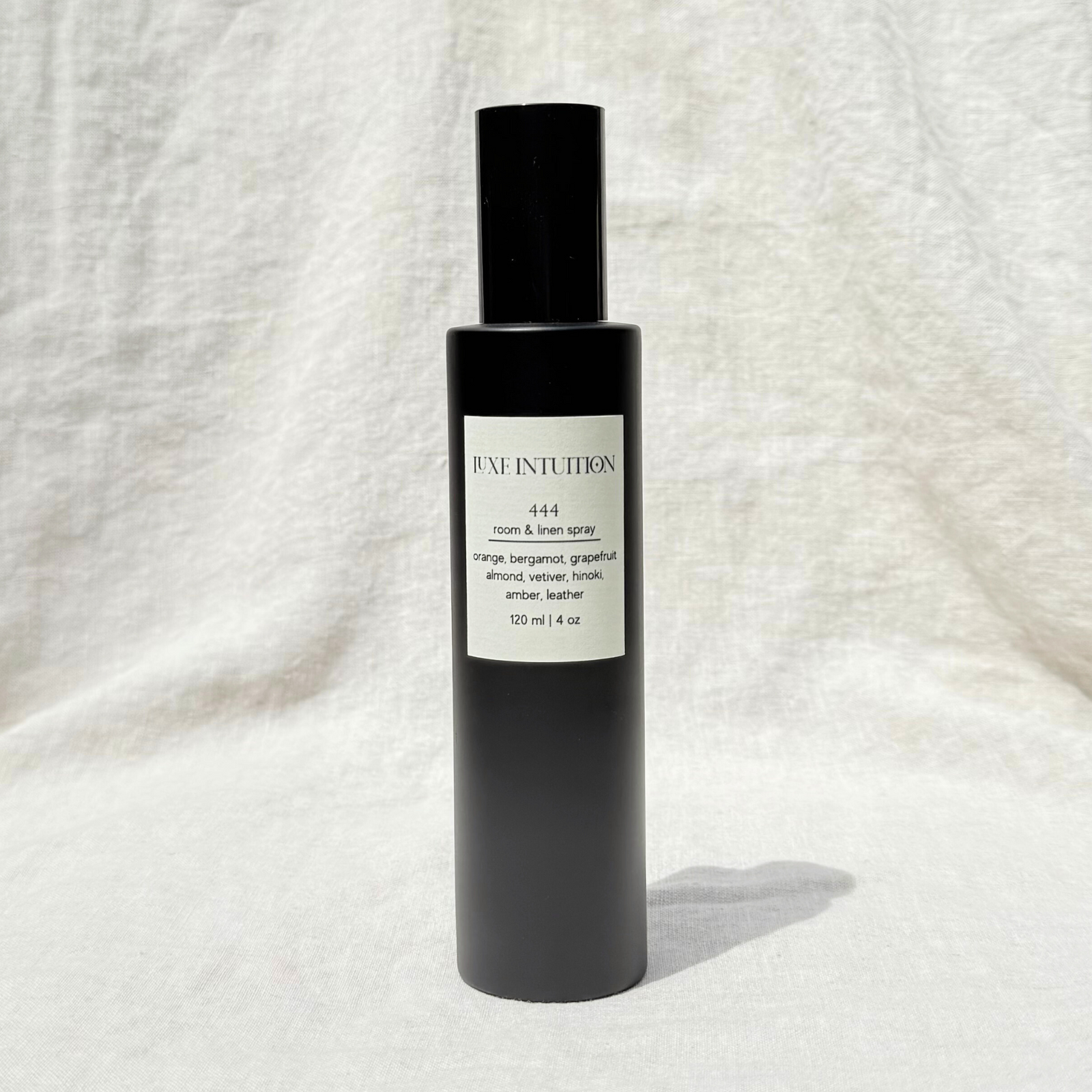 Orange and leather scented room & linen spray with a label that shows angel number 444 on a black spray bottle