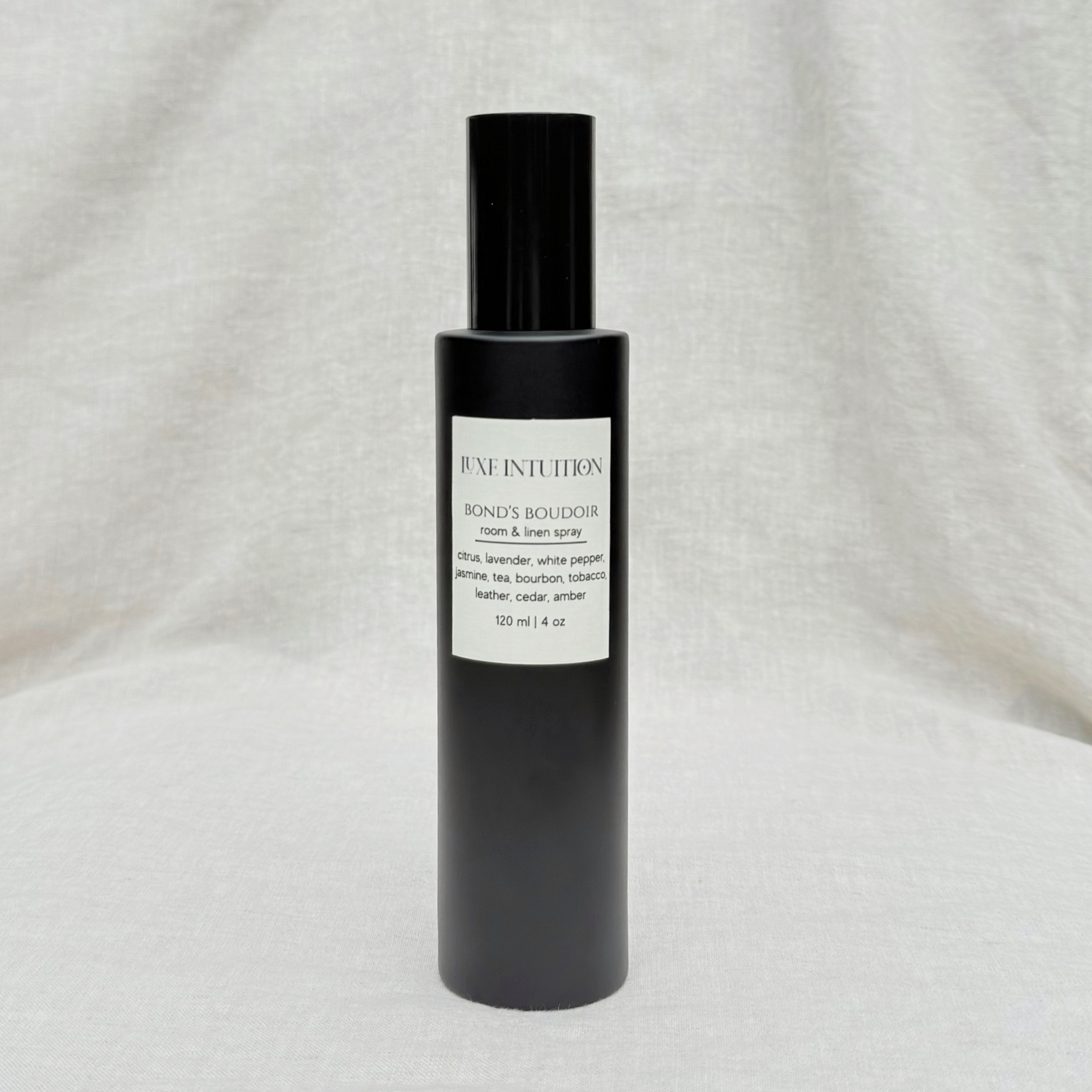 bourbon and leather scented room & linen spray in a black spray bottle on a linen background