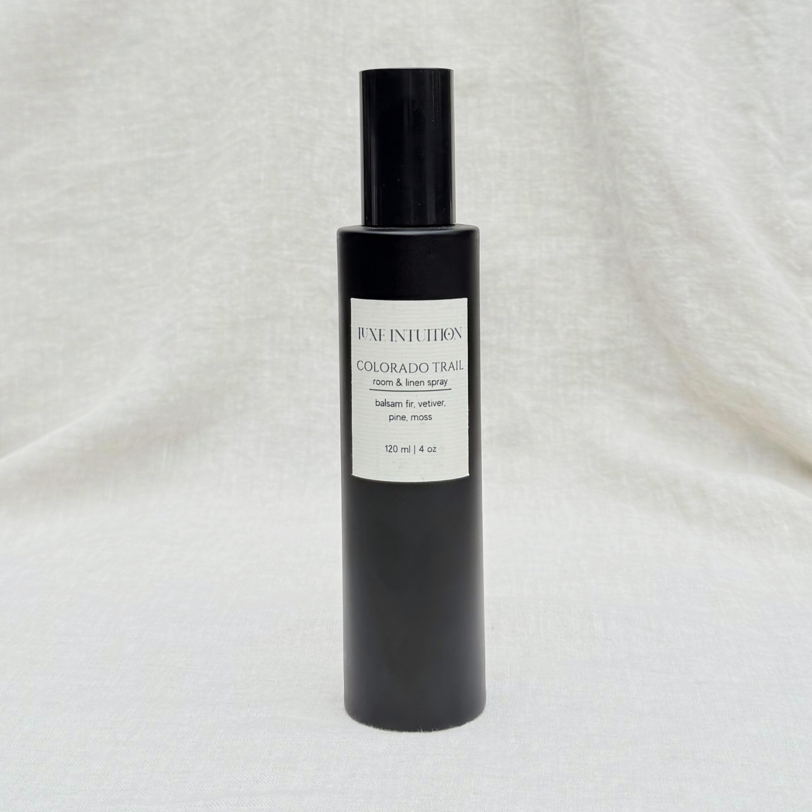 Pine and Vetiver scented room & linen spray in a black spray bottle on a linen background