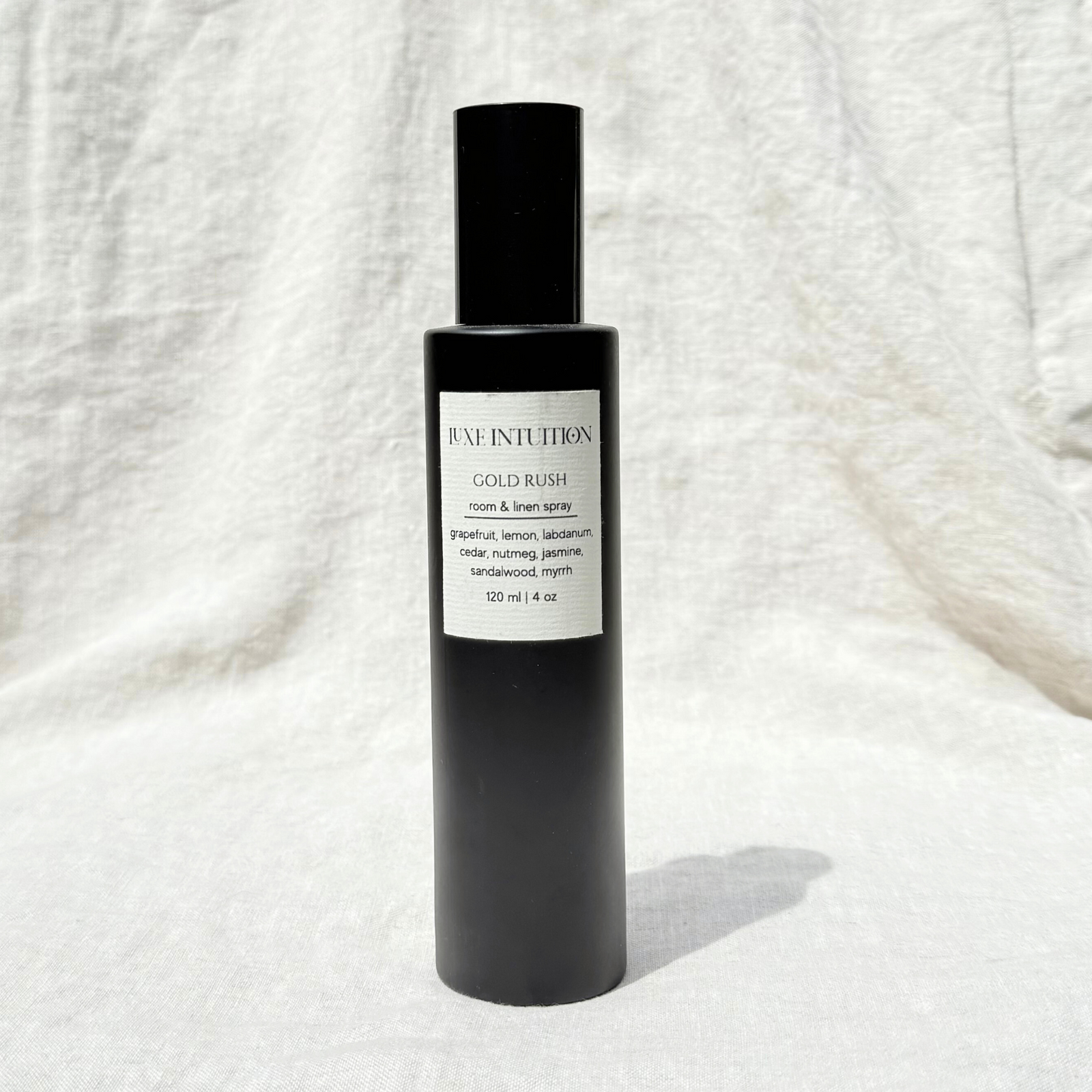 Grapefruit and sandalwood scented room & linen spray in a black spray bottle on a linen background