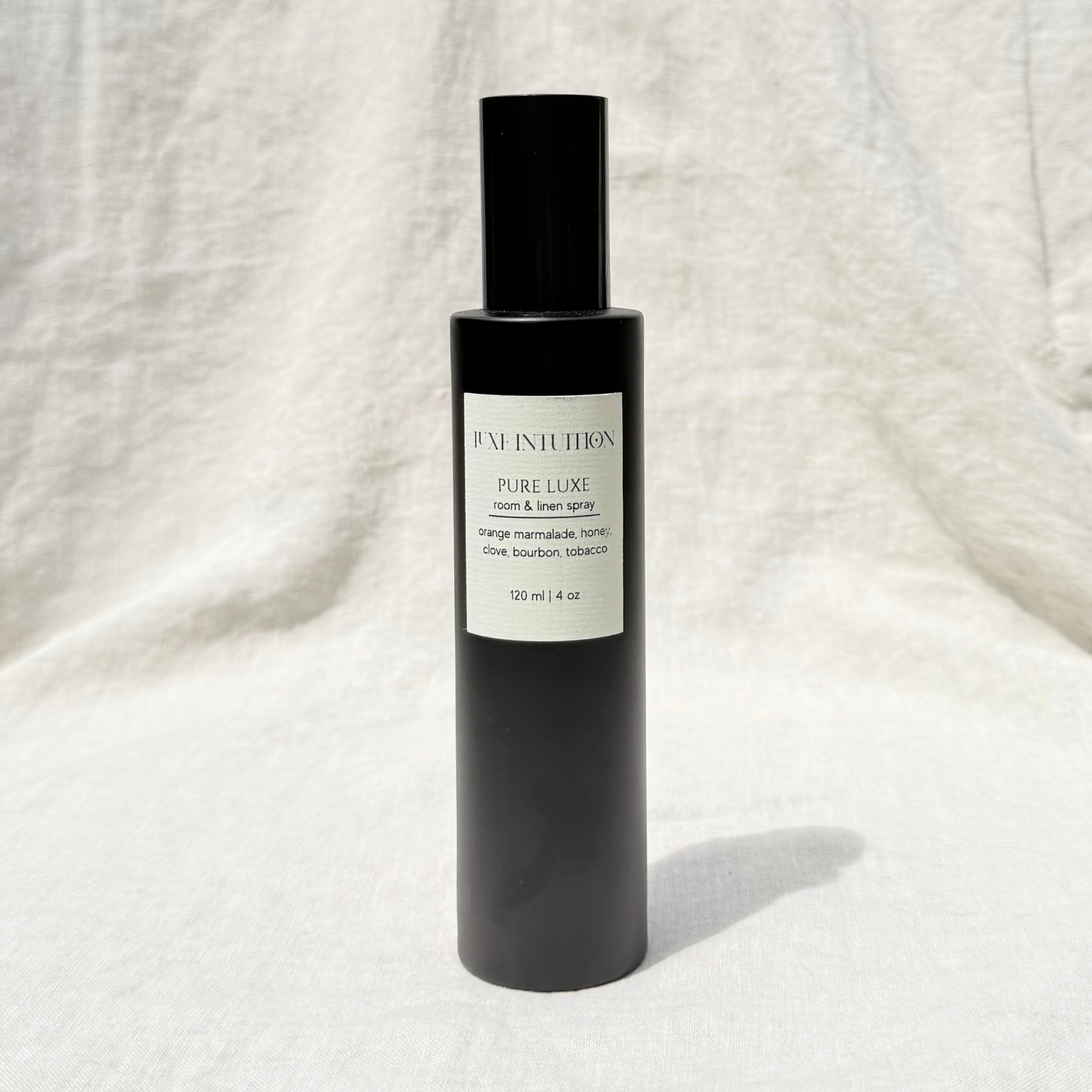 Honey and Bourbon scented toom & linen spray in a black spray bottle on a linen background