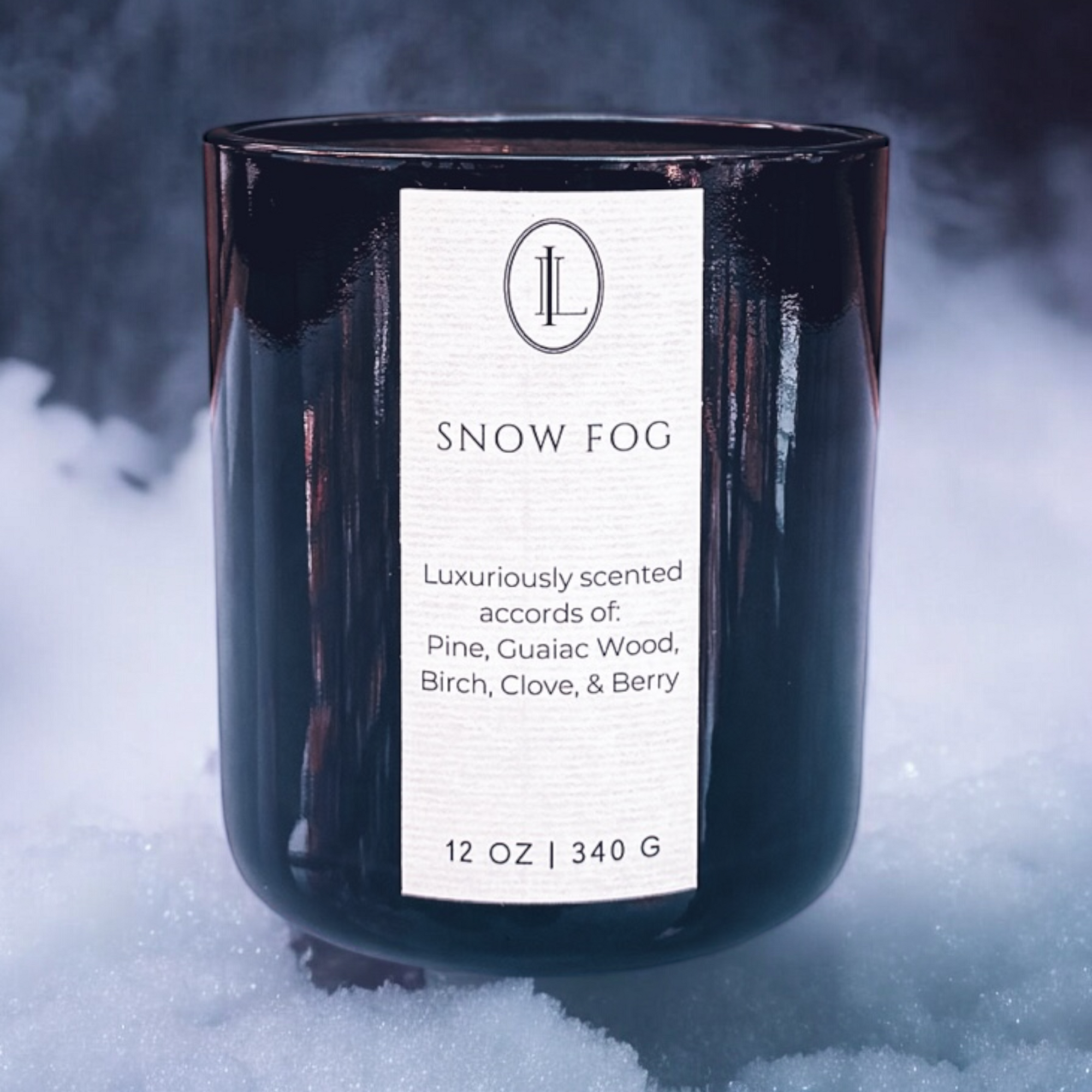 Snow Fog wood wick candle in a translucent black vessel sitting on snow with fog in the background