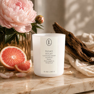 Hand-poured Peony Eclat limited-edition candle styled on marble with fresh pink peonies, sliced grapefruit, and aged oud wood — Colorado-made