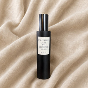 Hand-blended Agave Rose linen spray with Turkish rose, peach, and honey resting on natural linen fabric